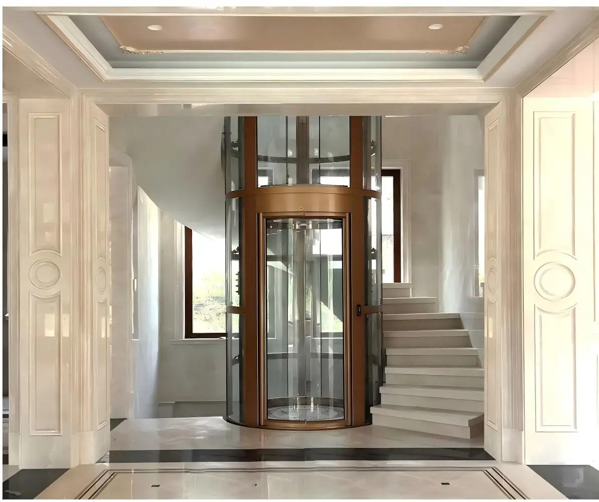 Thang máy hình trụ tròn, vách kính, với khung cửa và các chi tiết cabin sử dụng kim loại màu đồng